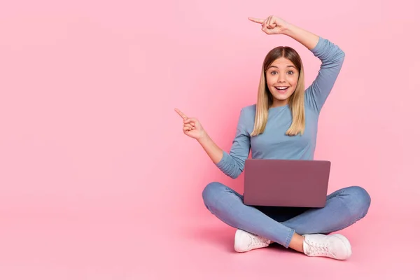 Pełny rozmiar zdjęcie młodej dziewczyny punkt palce puste miejsce promo polecam bezpośrednie siedzieć podłogi laptop izolowane na różowym tle kolor — Zdjęcie stockowe