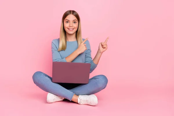 Pełne zdjęcie ciała młodej dziewczyny wskazują palcach pusty baner miejsca wybierz używać laptop siedzieć piętro izolowane nad różowym tle kolor — Zdjęcie stockowe