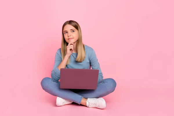 Pełne ciało zdjęcie młodej dziewczyny siedzieć podłoga ręka dotyk podbródek używać laptop przemyślany wygląd puste miejsce izolowane ponad różowy kolor tła — Zdjęcie stockowe