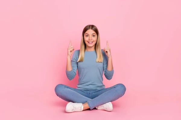 Pełnowymiarowe zdjęcie młodej dziewczyny siedzieć piętro wskazać palce puste miejsca reklamy zalecane sugerują izolowane na różowym tle koloru — Zdjęcie stockowe
