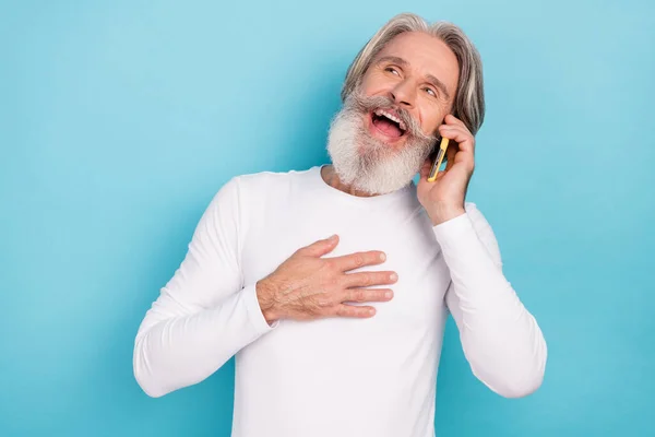 Çekici gri saçlı adamın portresi telefonda gülüyor, parlak mavi arka planda izole edilmiş eğleniyor. — Stok fotoğraf