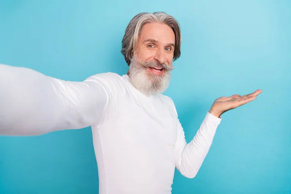 Autorretrato de atractivo hombre de pelo gris alegre sosteniendo en el espacio de copia de la palma anuncio aislado sobre fondo de color azul brillante — Foto de Stock