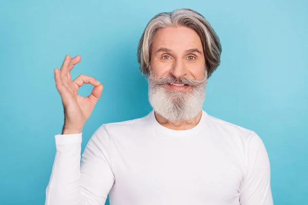 Портрет привлекательного веселого седого мужчины, показывающего рекламу на ярко-голубом фоне — стоковое фото
