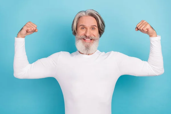 Retrato de atractivo alegre orgulloso hombre de pelo gris demostrando músculos aislados sobre fondo de color azul brillante — Foto de Stock
