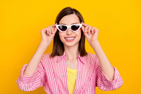 Photo of adorable glad positive lady arms touch sunglass beaming smile isolated on yellow color background — 图库照片