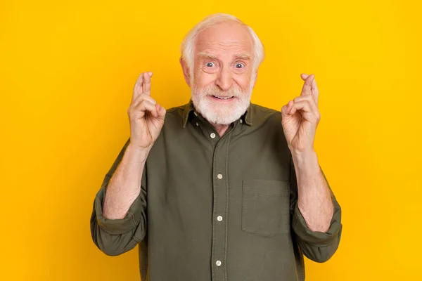 Retrato de pessoa idosa preocupada dois braços dedos cruzados dentes sorrir olhar câmera isolada no fundo de cor amarela — Fotografia de Stock
