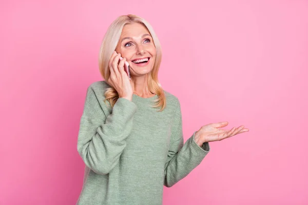 Güzel, yaşlı, sarışın bir bayanın telefon konuşması. Pembe arka planda izole edilmiş gri bir kazak giy. — Stok fotoğraf