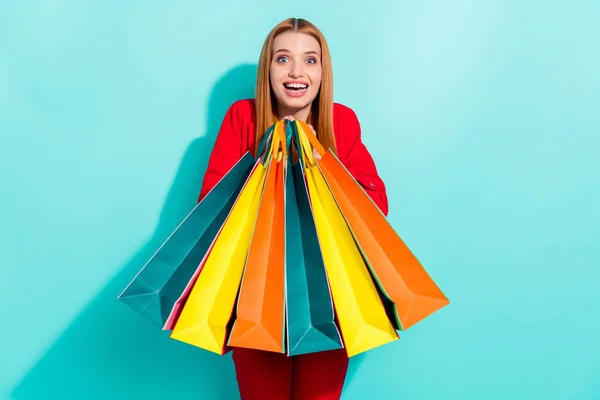 Foto van vrij onder de indruk oranje haar dame dragen rode blazer met kleurrijke boodschappentassen geïsoleerde cyaan kleur achtergrond — Stockfoto