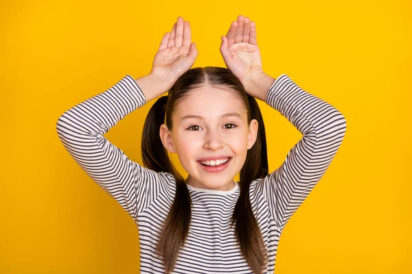 Foto de menina feliz sorriso positivo grimace segurar as mãos coelho orelhas coelho isolado sobre cor amarela fundo — Fotografia de Stock