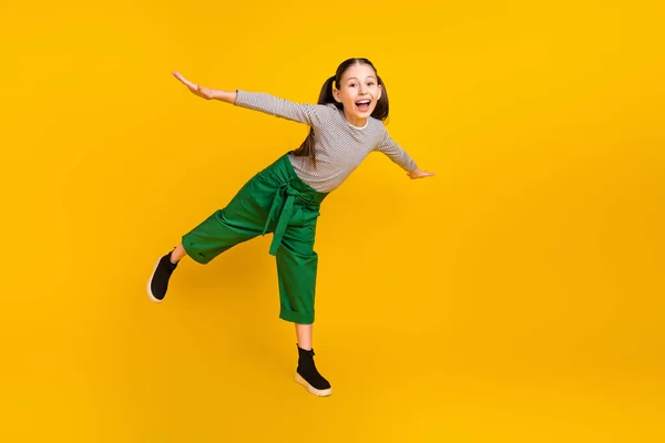 Foto de tamaño completo de niña de la escuela feliz sonrisa positiva manos alas volar aire aislado sobre fondo de color amarillo —  Fotos de Stock