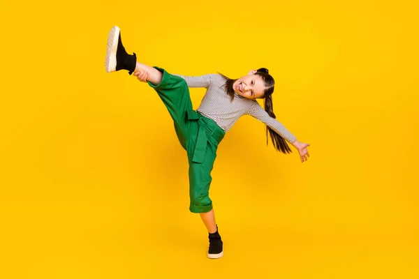Full längd foto av ung skola flicka glad positiv leende akrobatik träning isolerad över gul färg bakgrund — Stockfoto