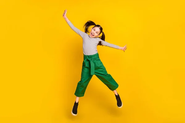 Полноразмерная фотография молодой возбужденной девушки с счастливой положительной улыбкой весело перепрыгивает через желтый цветной фон — стоковое фото