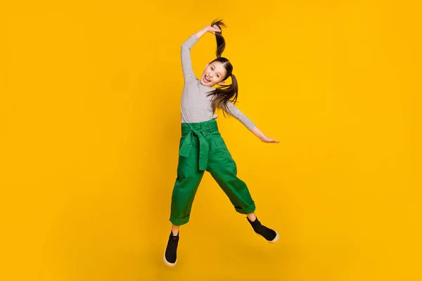 Foto corpo pieno di giovane ragazza eccitata scuola salto fino tenere coda di cavallo funky isolato su sfondo di colore giallo — Foto Stock