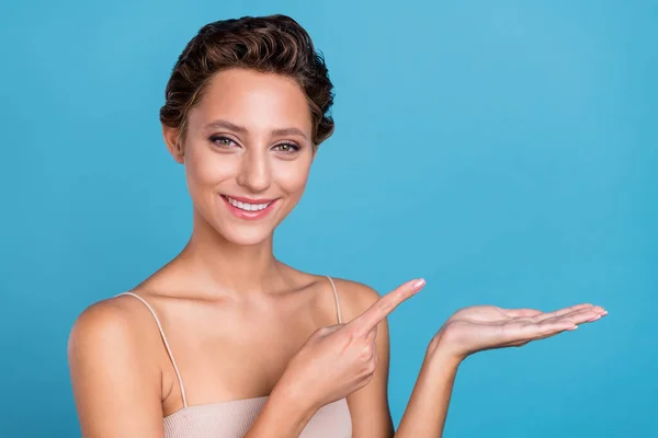 Retrato de chica alegre atractiva sosteniendo en la palma demostrando espacio de copia anuncio nuevo aislado sobre fondo de color azul vibrante — Foto de Stock