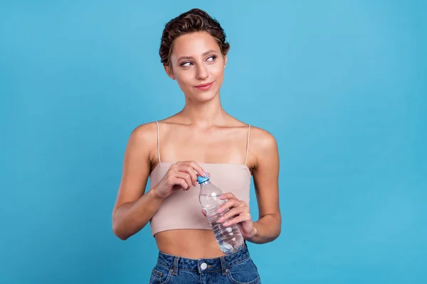 Foto van glimmende schattige jonge vrouw gekleed beige top drinkwater op zoek naar lege ruimte glimlachen geïsoleerde blauwe kleur achtergrond — Stockfoto