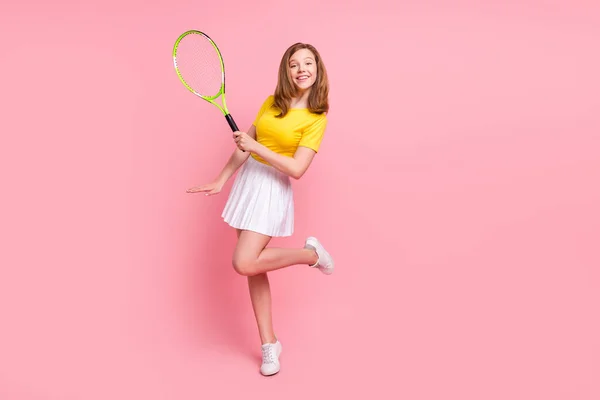 Foto de cuerpo completo de niña adolescente rubia agradable jugar tenis desgaste camiseta amarilla falda aislada sobre fondo de color rosa — Foto de Stock