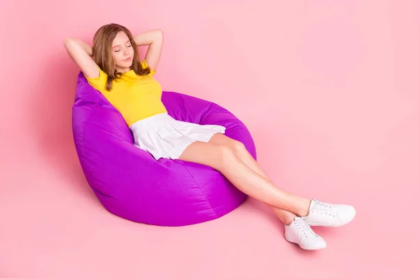 Full size profile side photo of young girl rest relax chair bean sleep nap hands behind head isolated over pink color background