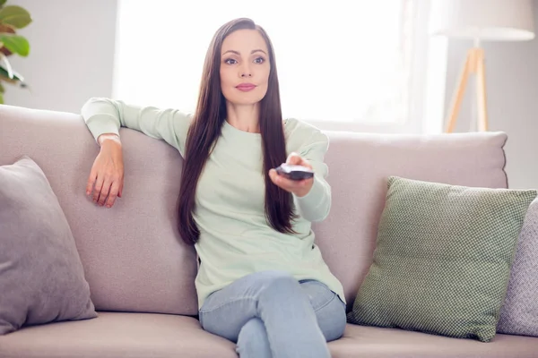 Photo of nice millennial brunette lady sit on sofa watch tv wear blue shirt at home alone — Foto Stock