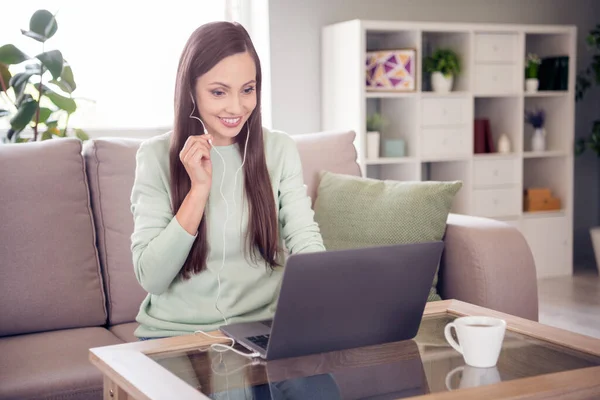 Photo of cute cheerful mature lady wear teal pullover smiling sitting couch talking modern gadget indoors house room — Stockfoto