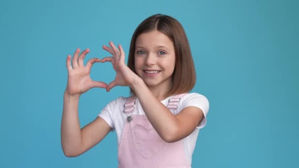 Cute schoolchild make hands romance heart isolated blue color background — Vídeo de Stock