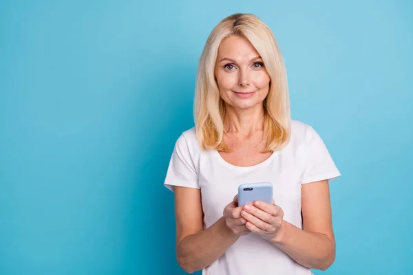 Modern yaşlı kadının fotoğrafı akıllı telefon mesajlaşması yorumu kullan, beyaz elbiseler giy, izole edilmiş mavi arka plan — Stok fotoğraf