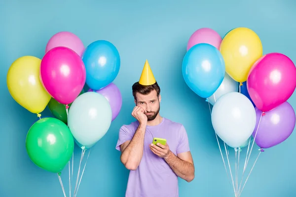 Foto-Porträt von traurigen Kerl berühren Gesicht Wange mit der Hand hält Telefon isoliert auf pastellblauem Hintergrund — Stockfoto