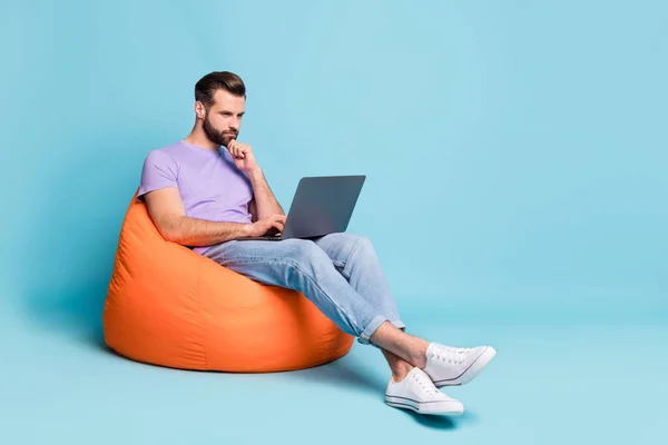 Foto de tamaño completo del cuerpo del hombre de negocios confiado que trabaja en la computadora en el bolso de frijoles aislado en el copyspace de fondo de color azul vibrante —  Fotos de Stock