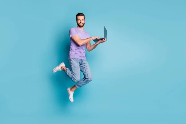 Pełna długość ciała rozmiar zdjęcie wesołych skoki student studiuje z komputerem uśmiechając się odizolowany na żywy niebieski kolor tła — Zdjęcie stockowe
