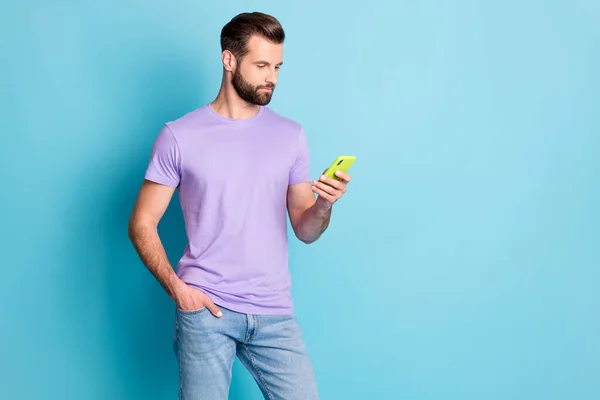 Retrato fotográfico del hombre serio enfocado que envía mensajes de texto a Internet con teléfono celular aislado en un fondo de color azul vivo con espacio en blanco —  Fotos de Stock