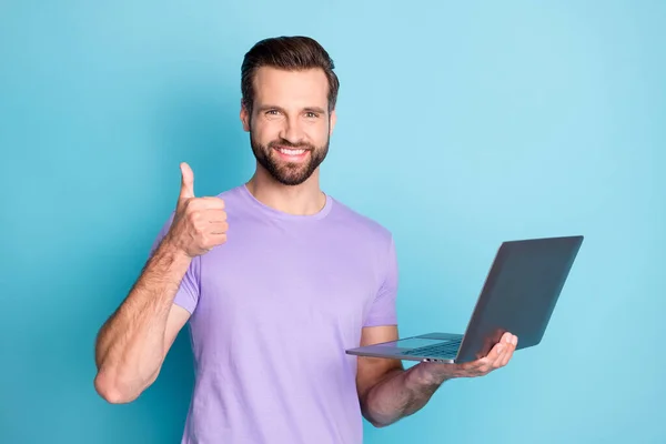 Photo portrait of smiling hipster keeping laptop showing like gesture doing project university isolated bright blue color background — 图库照片