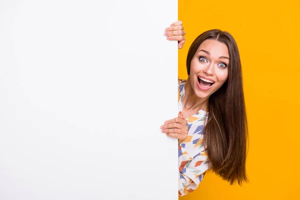 Portrait photo de fille folle se cachant derrière un mur blanc avec un espace vide isolé sur fond jaune vif — Photo