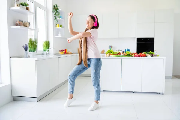 실내의 밝은 흰색 가정 부엌에서 재미를 즐기고 있는 유쾌 한 긴 머리 소녀가 춤을 추는 모습의 전체 몸길이 — 스톡 사진