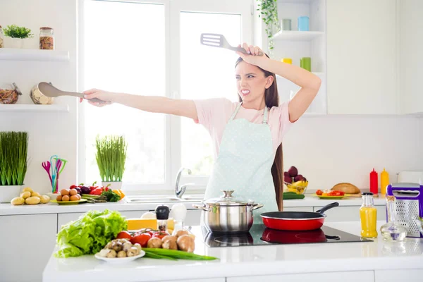 Portret van een aantrekkelijk speels meisje koken smakelijke maaltijd gourment hebben plezier vechten met lepel in licht wit huis keuken binnen — Stockfoto