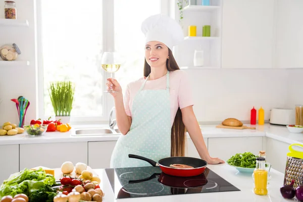 Портрет привабливої мрійливої веселої дівчини, що готує смачну смачну романтичну вечерю філе морепродуктів, що п'є вино на легкій білій домашній кухні в приміщенні — стокове фото