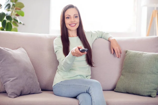 Photo of funny young brunette lady sit on sofa watch tv wear blue shirt at home alone — Foto Stock