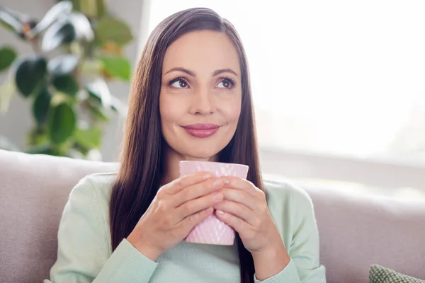 Foto van schattige jonge brunette dame zitten op bank drinken thee dragen blauw shirt alleen thuis — Stockfoto