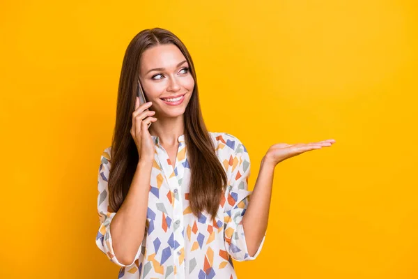 Foto retrato de mulher segurando olhando para o espaço em branco em uma mão falando no telefone isolado no fundo colorido amarelo vívido — Fotografia de Stock