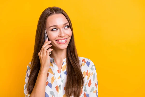 Telefondan konuşan mutlu bir kadının fotoğrafı. Açık sarı arka planda izole edilmiş boş bir alana bakıyor. — Stok fotoğraf