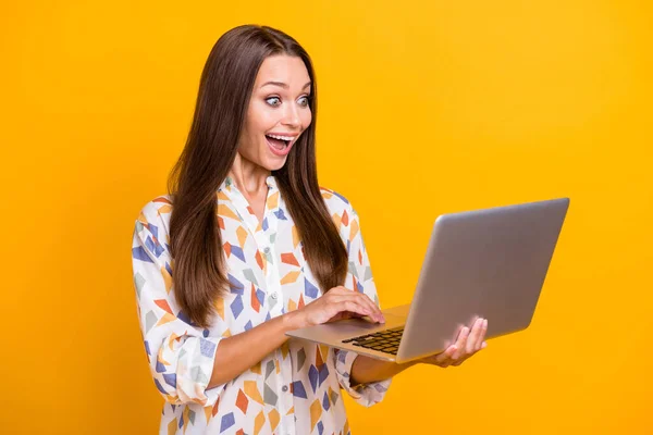 Foto portrét vzrušené dívky procházející internet držení notebook izolované na živém žlutém pozadí — Stock fotografie