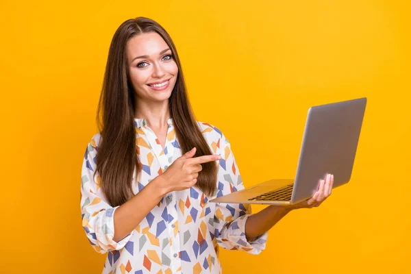 Photo portrait of woman pointing finger at laptop holding in hand isolated on vivid yellow colored background — Stock Photo, Image