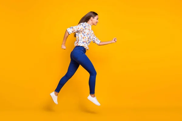 Photo portrait full body side view of running girl jumping up isolated on vivid yellow colored background — Foto Stock