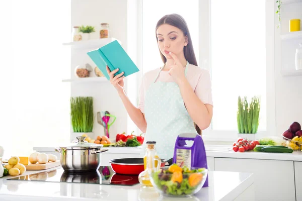 Πορτρέτο της ελκυστικής αβέβαιη σκεπτική κορίτσι μαγείρεμα νόστιμο γεύμα σούπα νεροκολοκύθα ανάγνωση βιβλίο Σαββατοκύριακο στο φως λευκό σπίτι κουζίνα σε εσωτερικούς χώρους — Φωτογραφία Αρχείου