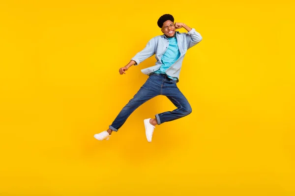 Foto von charmanten funky dunkle Haut Mann tragen Jeans-Shirt Springen hoch üben Karate isoliert gelbe Farbe Hintergrund — Stockfoto