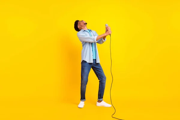 興奮したかわいい黒い肌の男の写真デニムシャツの歌マイクダンス孤立した黄色の背景 — ストック写真