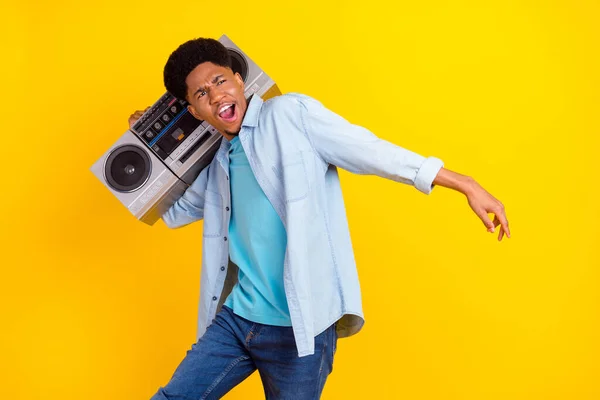 Photo of pretty cool dark skin man wear jeans shirt listening boombox singing dancing isolated yellow color background — Stockfoto