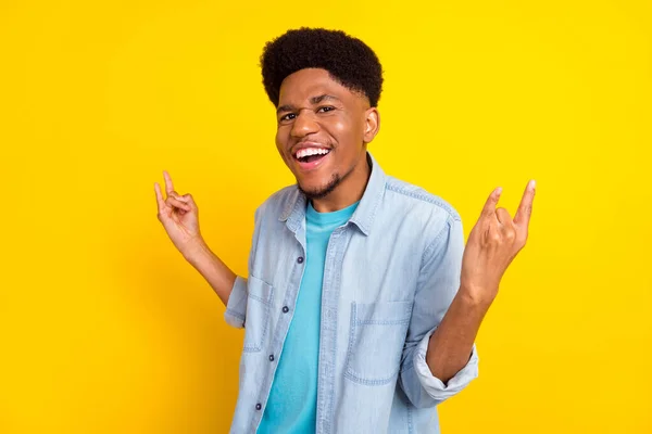 Photo of impressed funky dark skin man wear jeans shirt showing hard rock sign smiling isolated yellow color background — Foto Stock