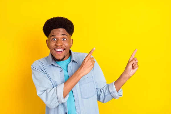 Foto von attraktiven beeindruckten dunkelhäutigen Mann tragen Jeans-Shirt lächelnd Zeigefinger leeren Raum isoliert gelbe Farbe Hintergrund — Stockfoto