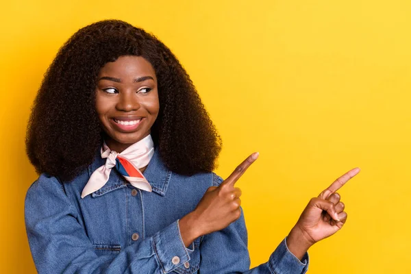 Retrato de mujer de piel oscura positiva mira dedos directos espacio vacío proposición aislada sobre fondo de color amarillo —  Fotos de Stock