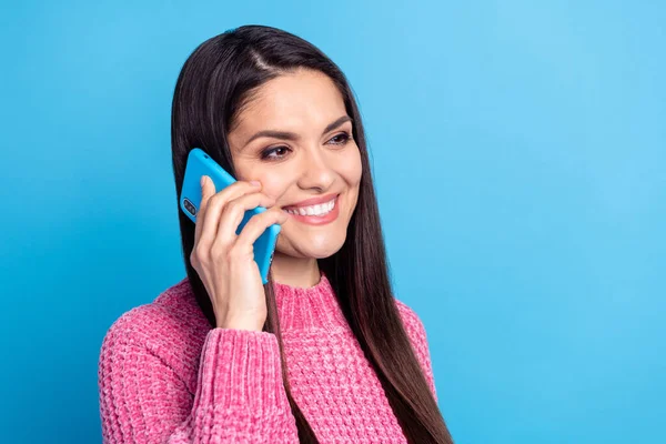 Photo of shiny pretty young lady dressed pink sweater talking modern gadget isolated blue color background — стоковое фото