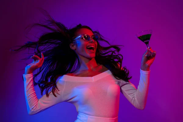 Photo of funky millennial brunette lady drink alcohol look promo wearing white dress spectacles isolated over neon color background — Foto Stock